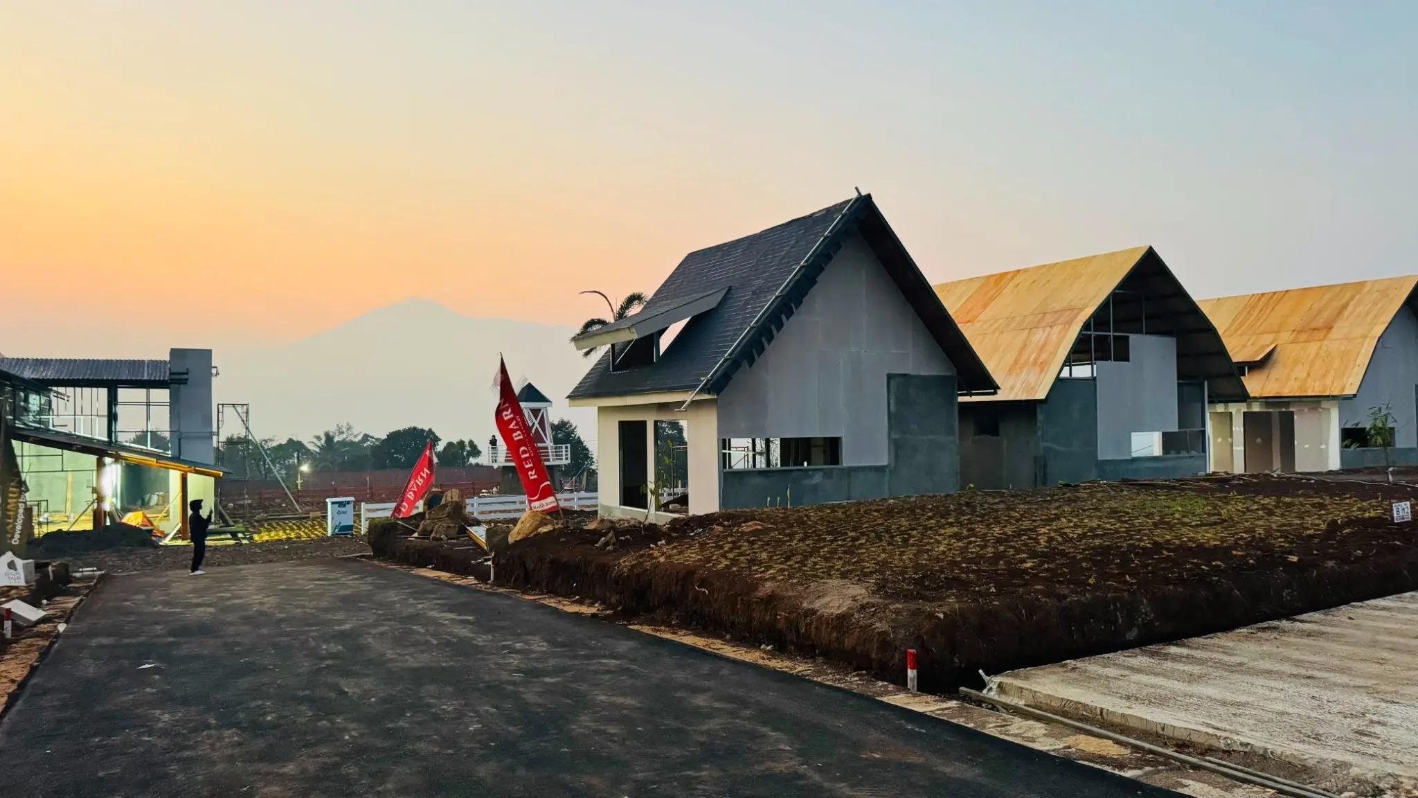 Progres pembangunan kawasan Nuansa Alam dengan latar pegunungan saat senja